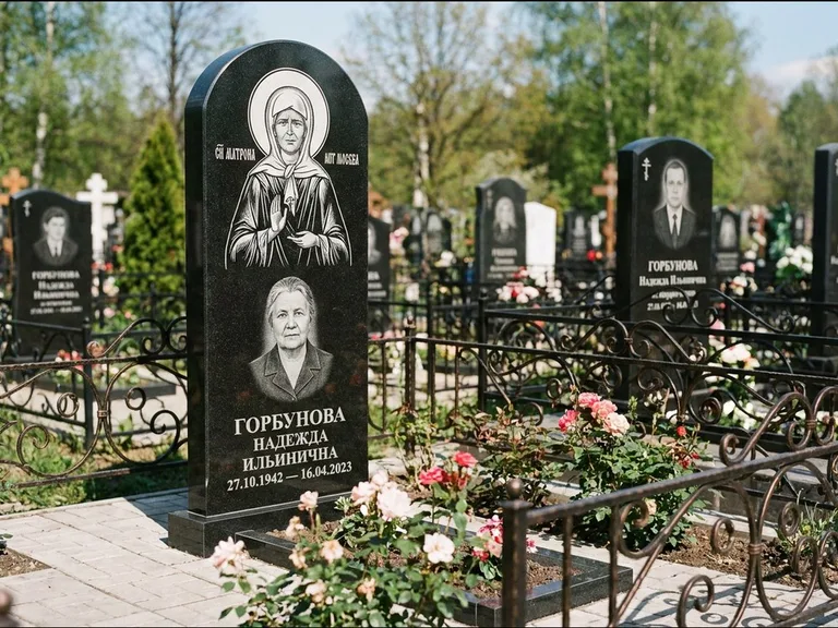 Памятник с гравировкой иконы: стела с арочным верхом и киотом под образ — гравировка образа Матроны Московской, гранитный цоколь с тёмной плиткой, работа «Ковалёв» в Ярославле