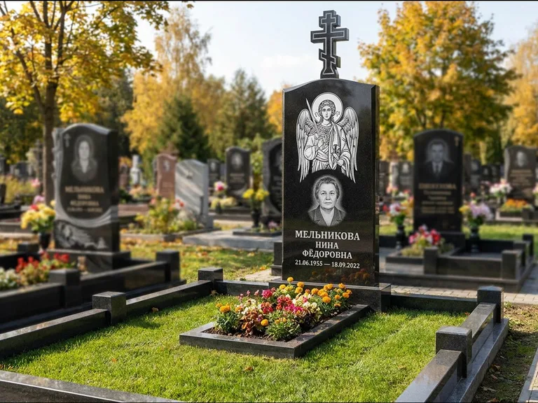 Памятник с гравировкой иконы: округлая стела-медальон с ликом — гравировка Богородицы «Семистрельная», луговые травы и полевые цветы за участком, работа «Гущин» в Ярославле