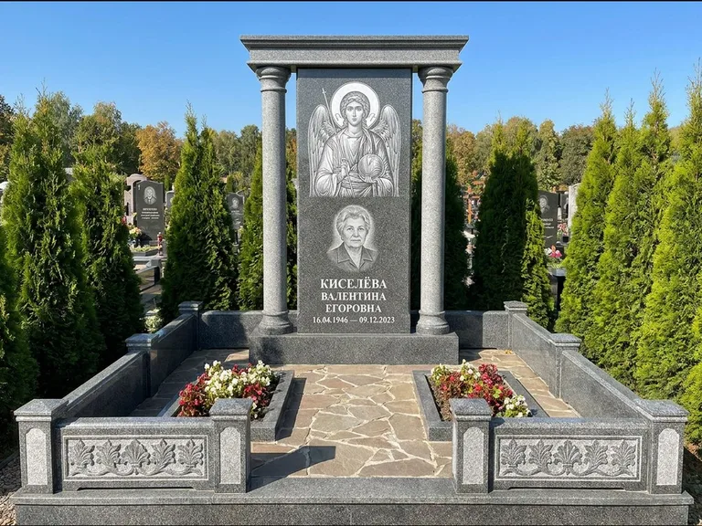 Памятник с гравировкой иконы: массивная стела с двускатным навершием-домиком — гравировка Николая Чудотворца, живая изгородь из туи, работа «Журавлёв» в Ярославле