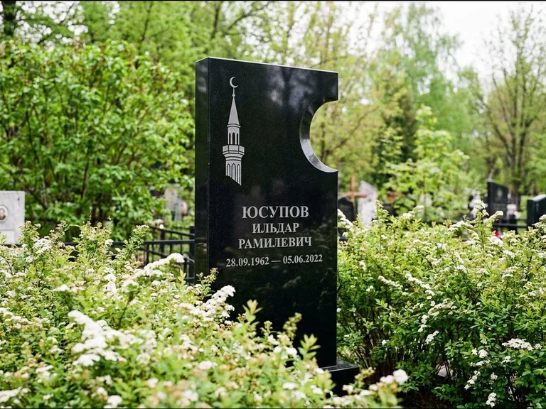 Мусульманский памятник с гравировкой мечети: стела с боковым вырезом в форме полумесяца — гравировка минарета с полумесяцем, низкие кусты спиреи в цвету, работа «Юсупов» в Ярославле