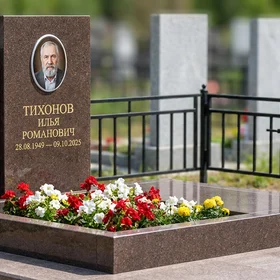 Гранитный памятник строгой формы с оградой